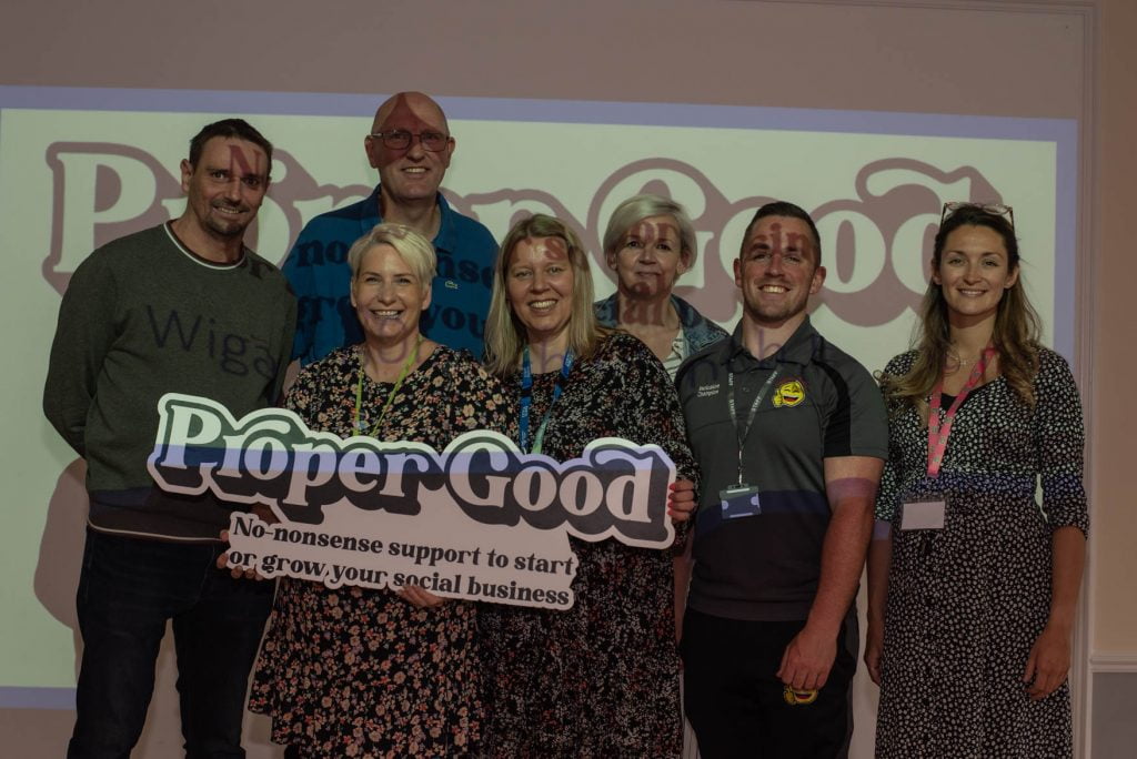 A group of guests holding the Proper Good sign together at the launch event