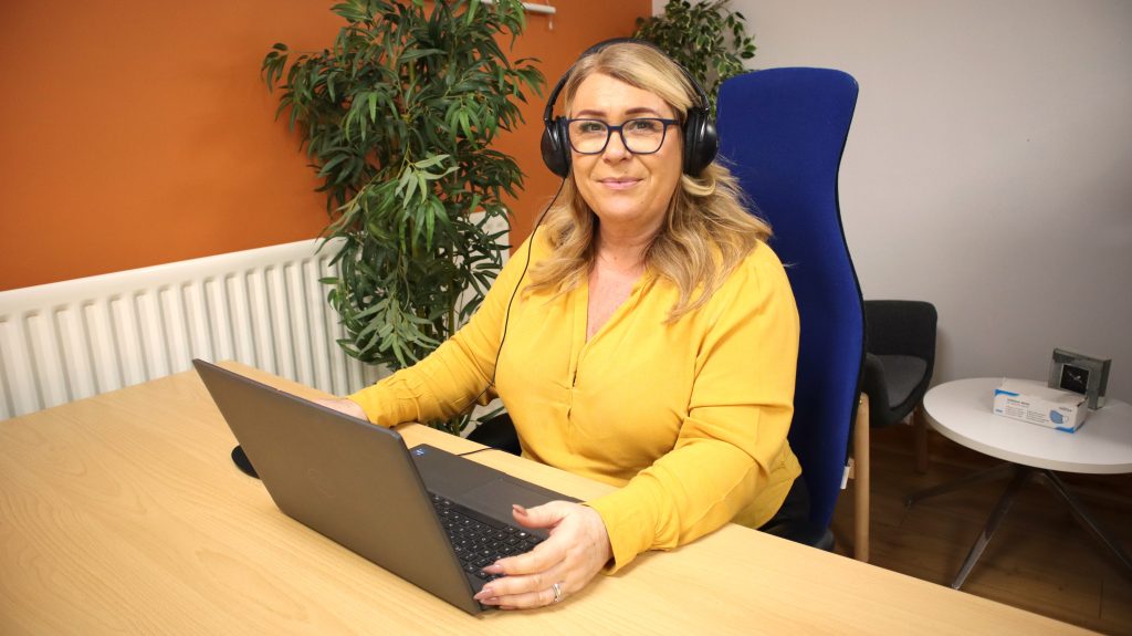 A Making Space team member working at a laptop in the office, wearing a headset