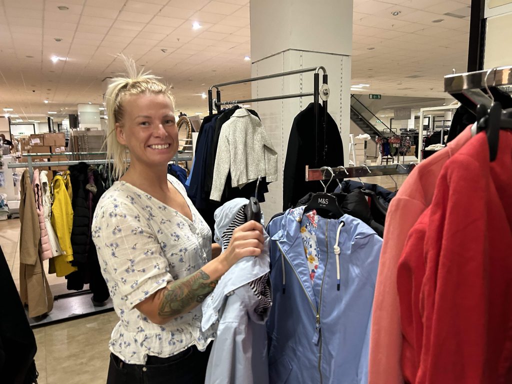 A volunteer sorting donated clothing on the rails at the Rebuild With Hope store