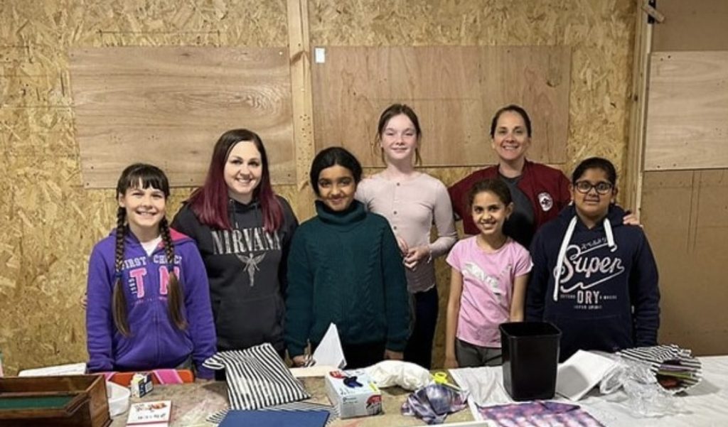 Young people and volunteers gathered around the craft table at a workshop session